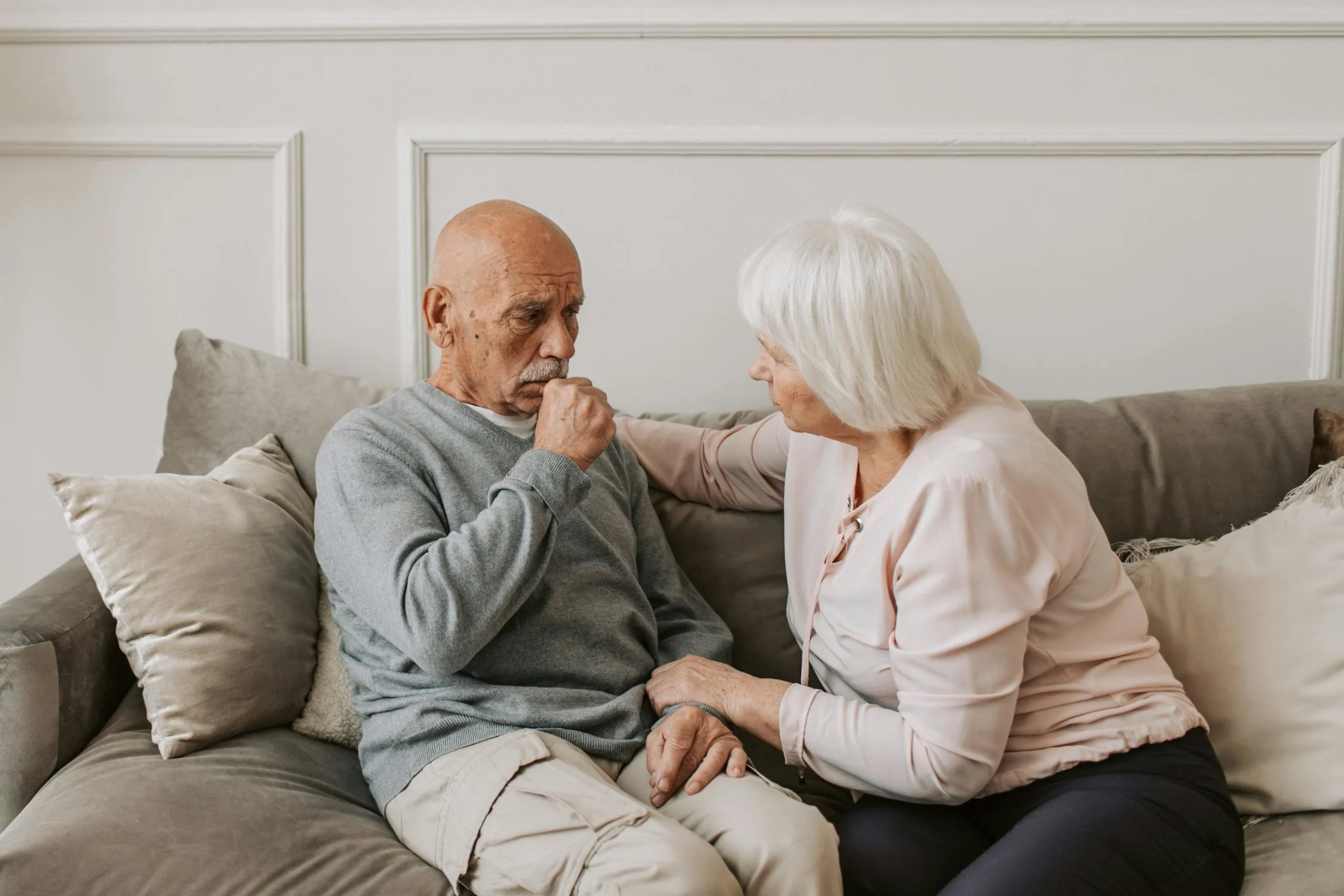 Elderly man coughing with supportive caregiver beside him